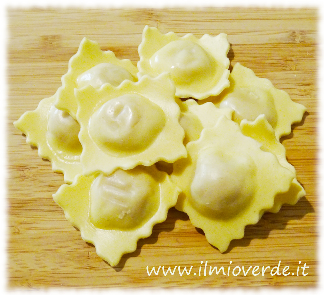 Una manciata di ravioli freschi disposti su un tagliere di legno, pronti per essere cucinati.